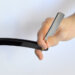 A male hand holding a black-handled straight razor on a white backgound