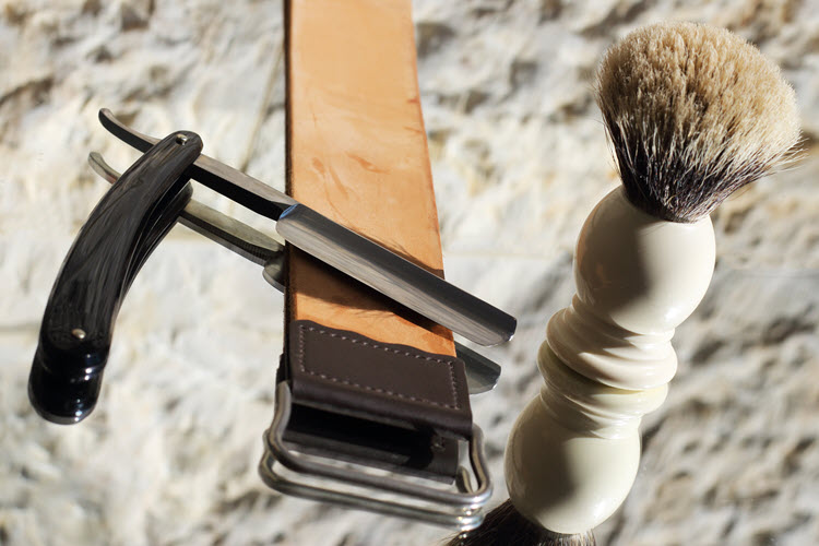 A image of a straight razor, strop, and shaving brush