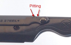 Pitting located on the blade arm clip next to the attachment pin.