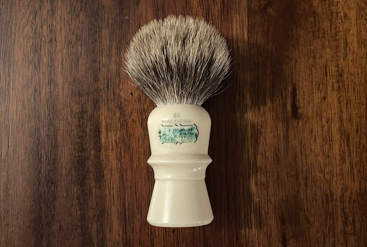 A picture of a Simpson Beaufort B4 pure badger shaving brush laying  on it's side on a wooden surface.