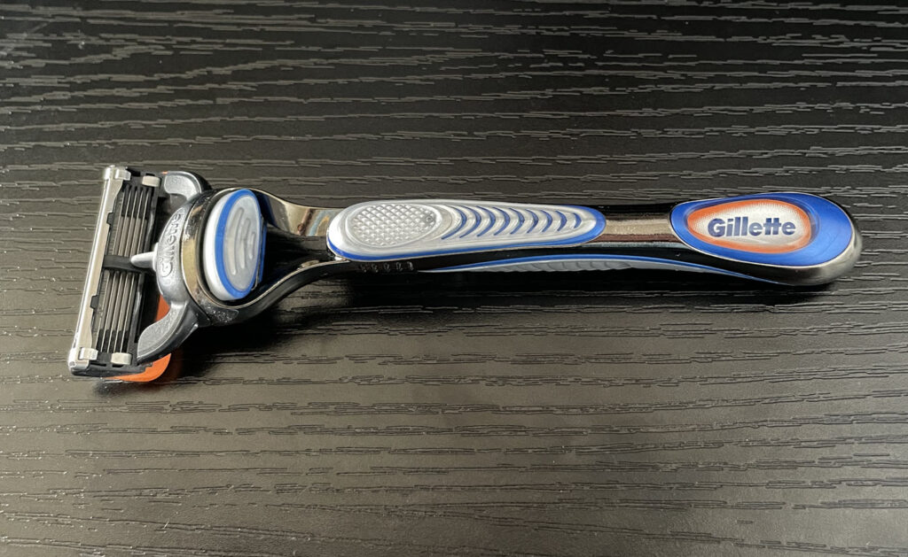 Gillette Fusion 5 razor sitting on a black faux wood surface.
